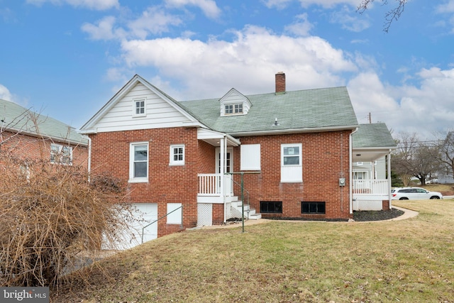 rear view of house with brick siding, a yard, a chimney, and an attached garage