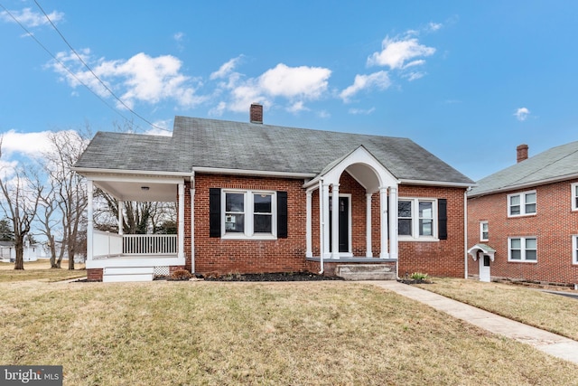 bungalow-style home featuring a porch, a shingled roof, brick siding, a front lawn, and a chimney