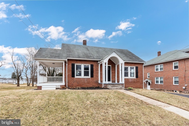 bungalow-style house featuring covered porch, brick siding, a chimney, and a front yard