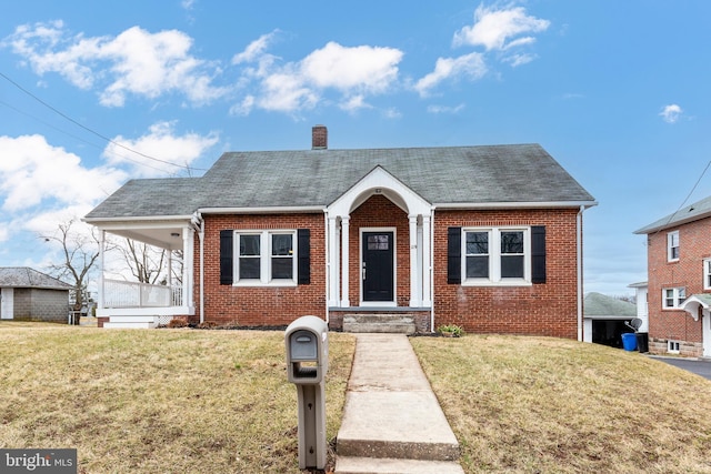 bungalow-style home with brick siding, a front lawn, and a chimney