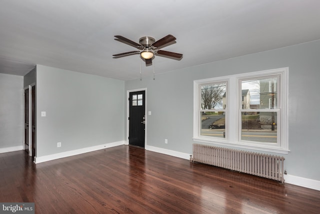 unfurnished living room featuring radiator, ceiling fan, baseboards, and wood finished floors