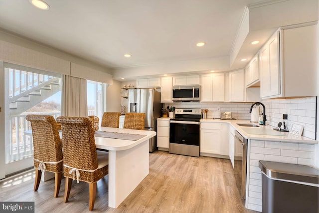 kitchen with decorative backsplash, appliances with stainless steel finishes, light countertops, white cabinetry, and a sink