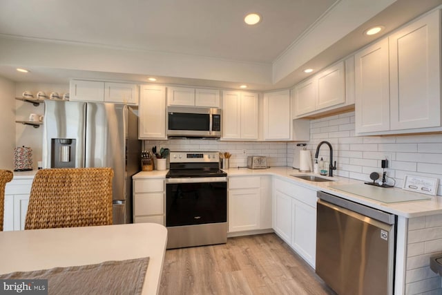 kitchen with light countertops, appliances with stainless steel finishes, a sink, and white cabinets