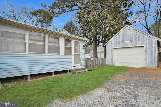 view of property exterior with a detached garage, a lawn, fence, an outdoor structure, and driveway