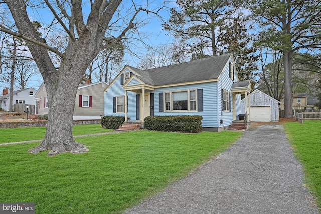 bungalow-style home with driveway, a front lawn, an outdoor structure, and a detached garage