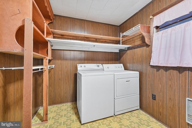 washroom featuring laundry area, wood walls, light floors, and washer and clothes dryer