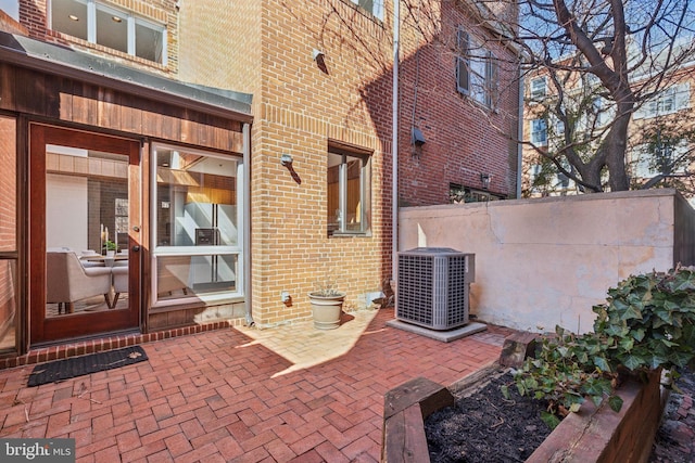 property entrance featuring brick siding, cooling unit, and a patio