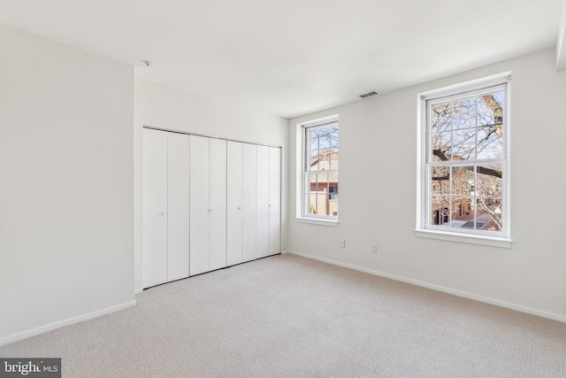 unfurnished bedroom with a closet, visible vents, baseboards, and carpet