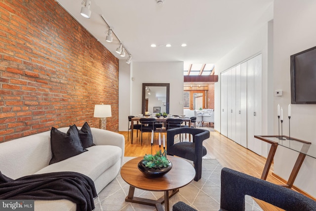 living area featuring recessed lighting, light wood-style floors, and brick wall