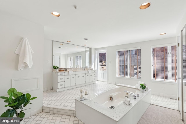 bathroom with recessed lighting, baseboards, a tub with jets, and vanity