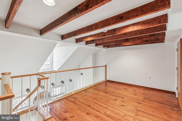 bonus room with hardwood / wood-style floors and vaulted ceiling with beams