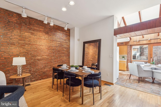 dining area with visible vents, brick wall, and light wood-style floors