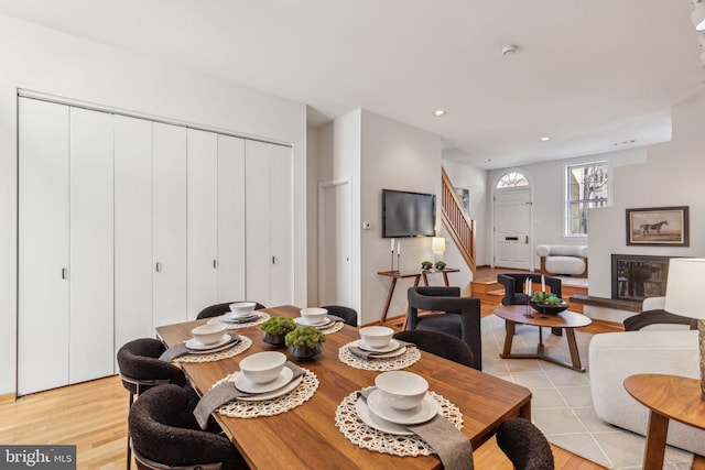 dining area with stairs, a glass covered fireplace, recessed lighting, and light wood-style floors