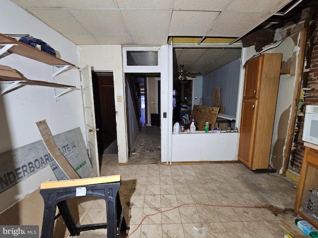 interior space with a paneled ceiling and brown cabinets