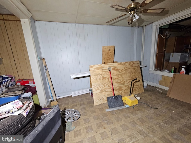 misc room featuring ceiling fan, wood walls, and tile patterned floors