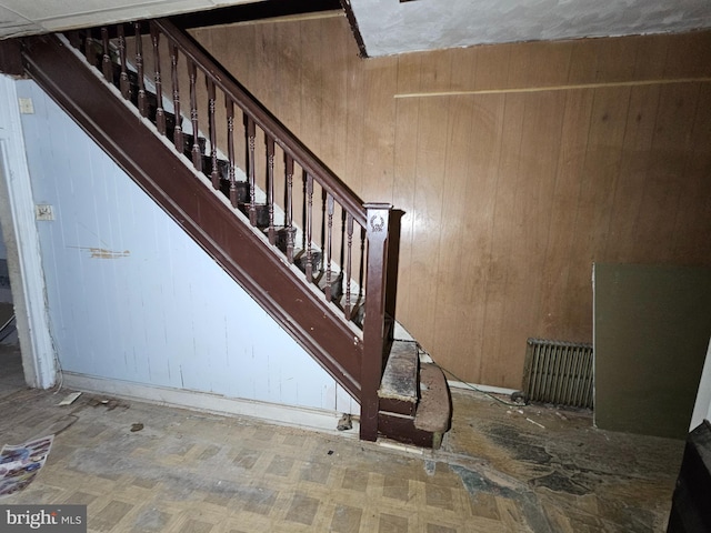 staircase featuring wood walls