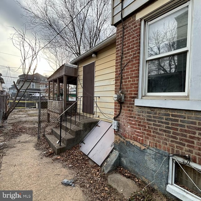 entrance to property featuring brick siding and fence