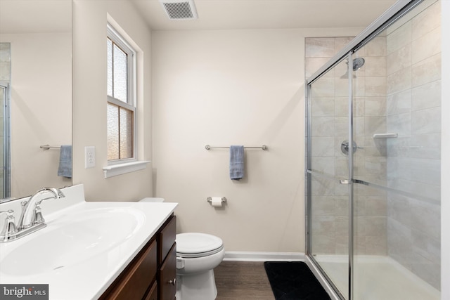 bathroom with toilet, wood finished floors, visible vents, baseboards, and a shower stall