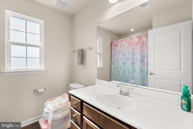 full bath featuring curtained shower, visible vents, toilet, vanity, and baseboards