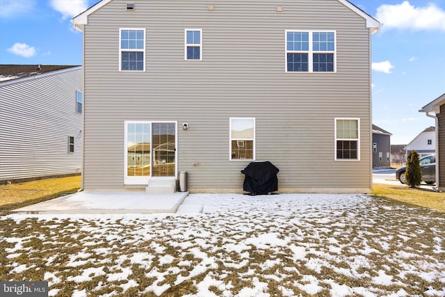 snow covered rear of property featuring a patio area