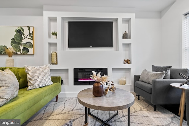 living area with a glass covered fireplace and built in features