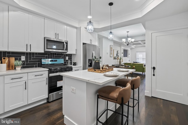 kitchen featuring light stone counters, stainless steel appliances, a kitchen island, white cabinets, and crown molding