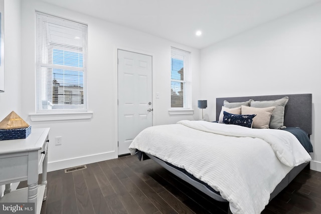 bedroom featuring dark wood-style floors, visible vents, multiple windows, and baseboards