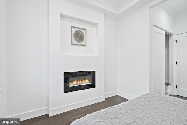 bedroom with crown molding, baseboards, dark wood-type flooring, and a glass covered fireplace