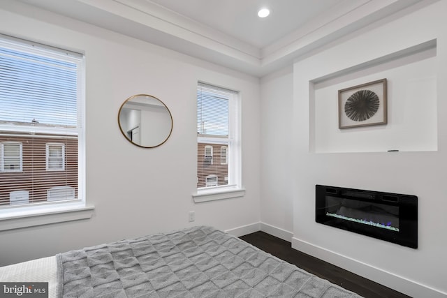 unfurnished bedroom with dark wood-style flooring, recessed lighting, a glass covered fireplace, and baseboards