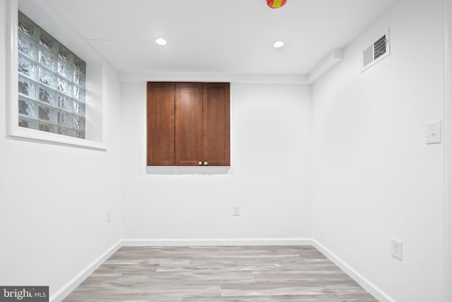 spare room with light wood-type flooring, visible vents, and baseboards