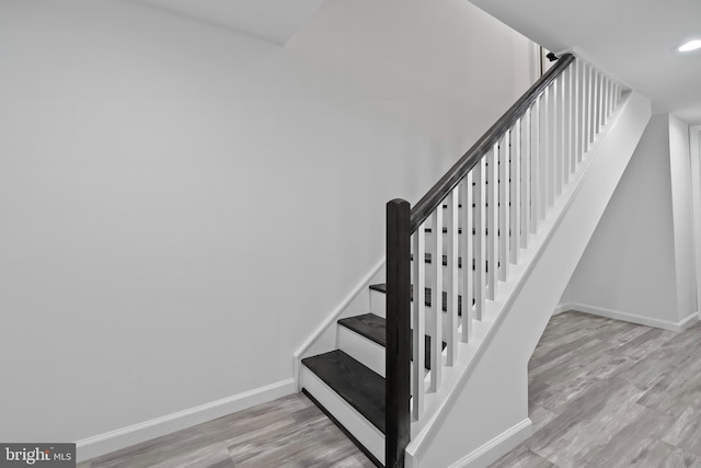 stairway featuring baseboards, wood finished floors, and recessed lighting