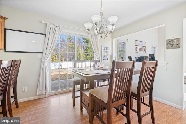 dining room with a chandelier, baseboards, and light wood finished floors