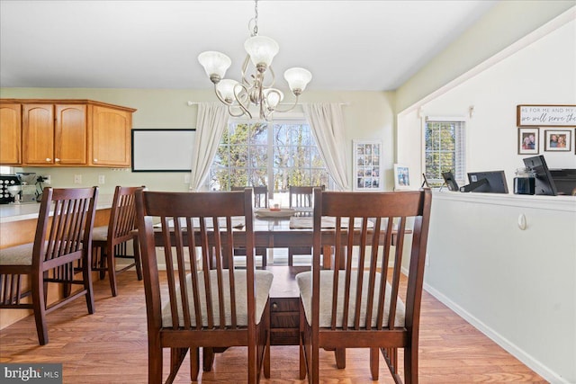 dining room featuring baseboards, a notable chandelier, and light wood finished floors