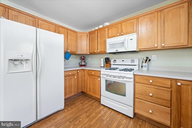 kitchen featuring brown cabinets, white appliances, light countertops, and wood finished floors