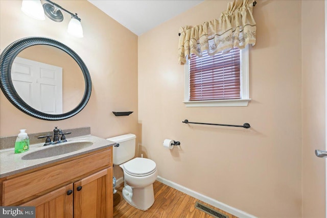 bathroom featuring visible vents, toilet, vanity, wood finished floors, and baseboards