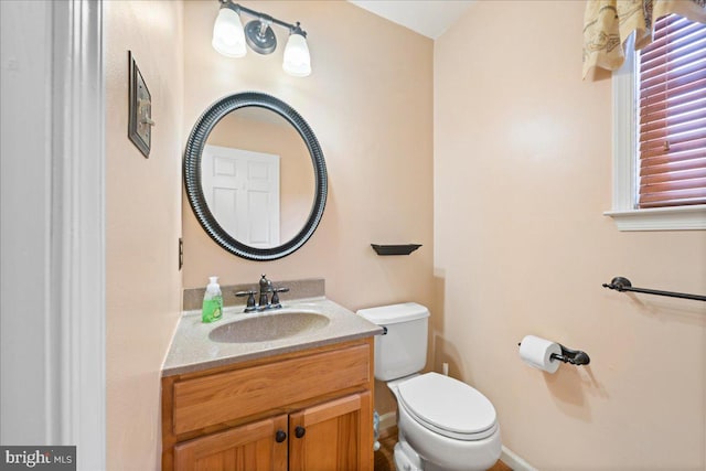 bathroom featuring toilet, vanity, and baseboards