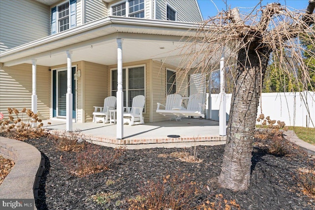 rear view of house featuring covered porch and fence