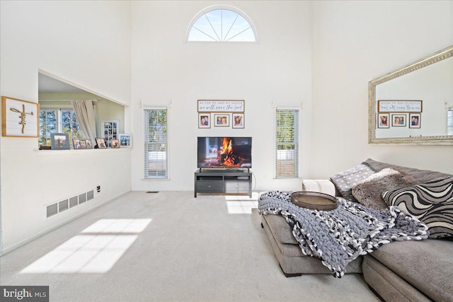 carpeted living room featuring visible vents and a high ceiling