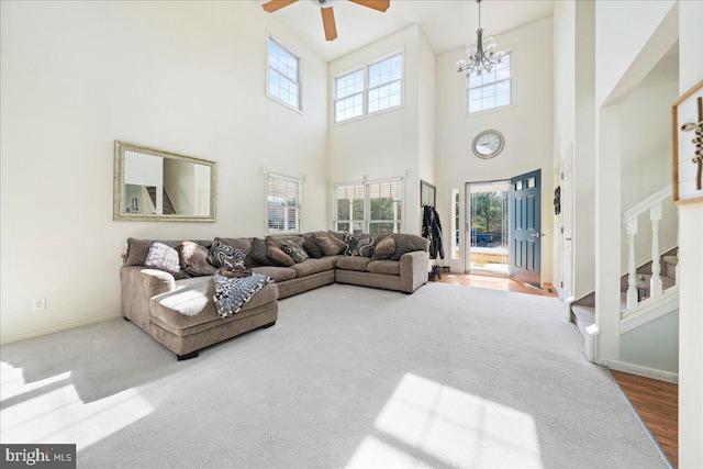 carpeted living room with ceiling fan with notable chandelier, stairway, plenty of natural light, and baseboards