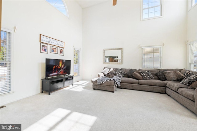 carpeted living room featuring a towering ceiling and baseboards