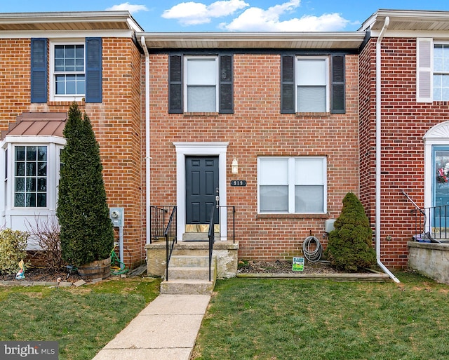 townhome / multi-family property featuring brick siding and a front yard