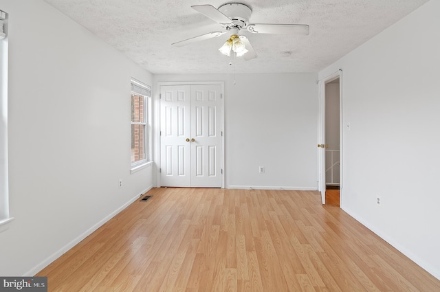 unfurnished bedroom featuring baseboards, visible vents, light wood-style flooring, a textured ceiling, and a closet