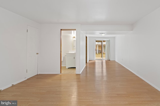 unfurnished room with light wood-type flooring and baseboards