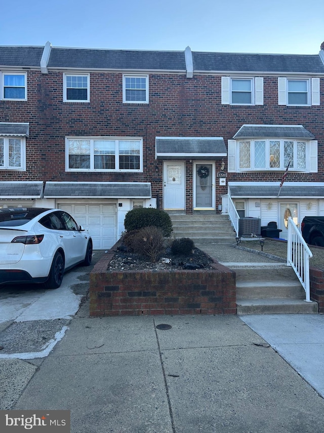 townhome / multi-family property featuring a garage, driveway, and brick siding