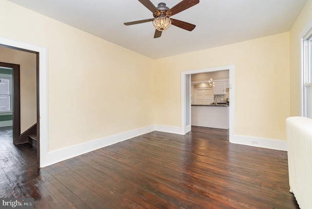 unfurnished room with baseboards, ceiling fan, dark wood-style flooring, and radiator