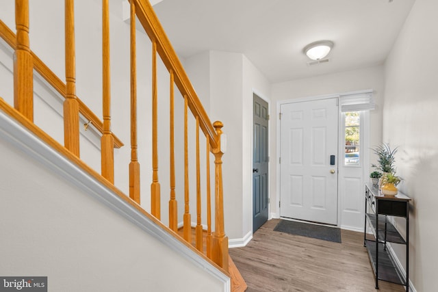 foyer featuring baseboards, stairs, visible vents, and wood finished floors