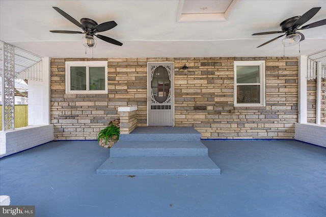 doorway to property featuring a ceiling fan, stone siding, and brick siding