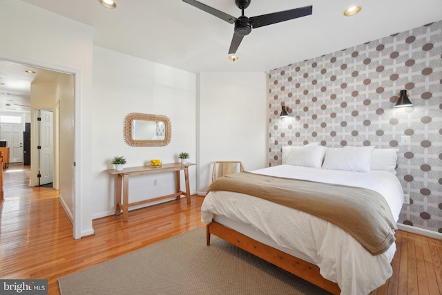 bedroom with an accent wall, baseboards, wood finished floors, and recessed lighting