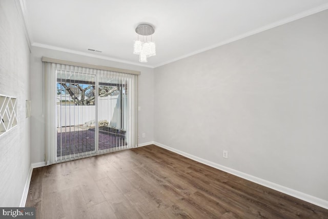 spare room featuring visible vents, a notable chandelier, wood finished floors, crown molding, and baseboards