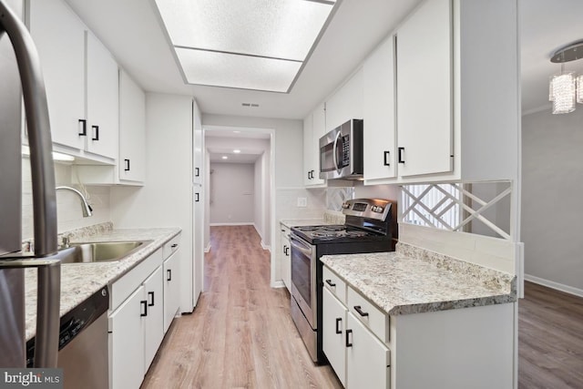 kitchen featuring white cabinetry, light wood-style flooring, a sink, and stainless steel appliances